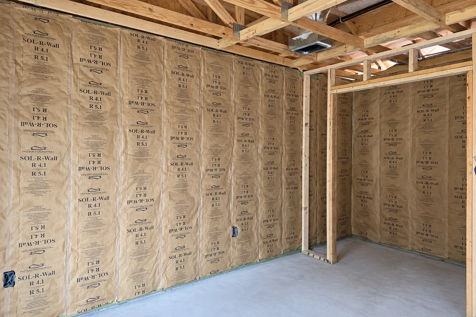 Paper-faced fiberglass batts fill the exposed wall cavities of an unfinished room.